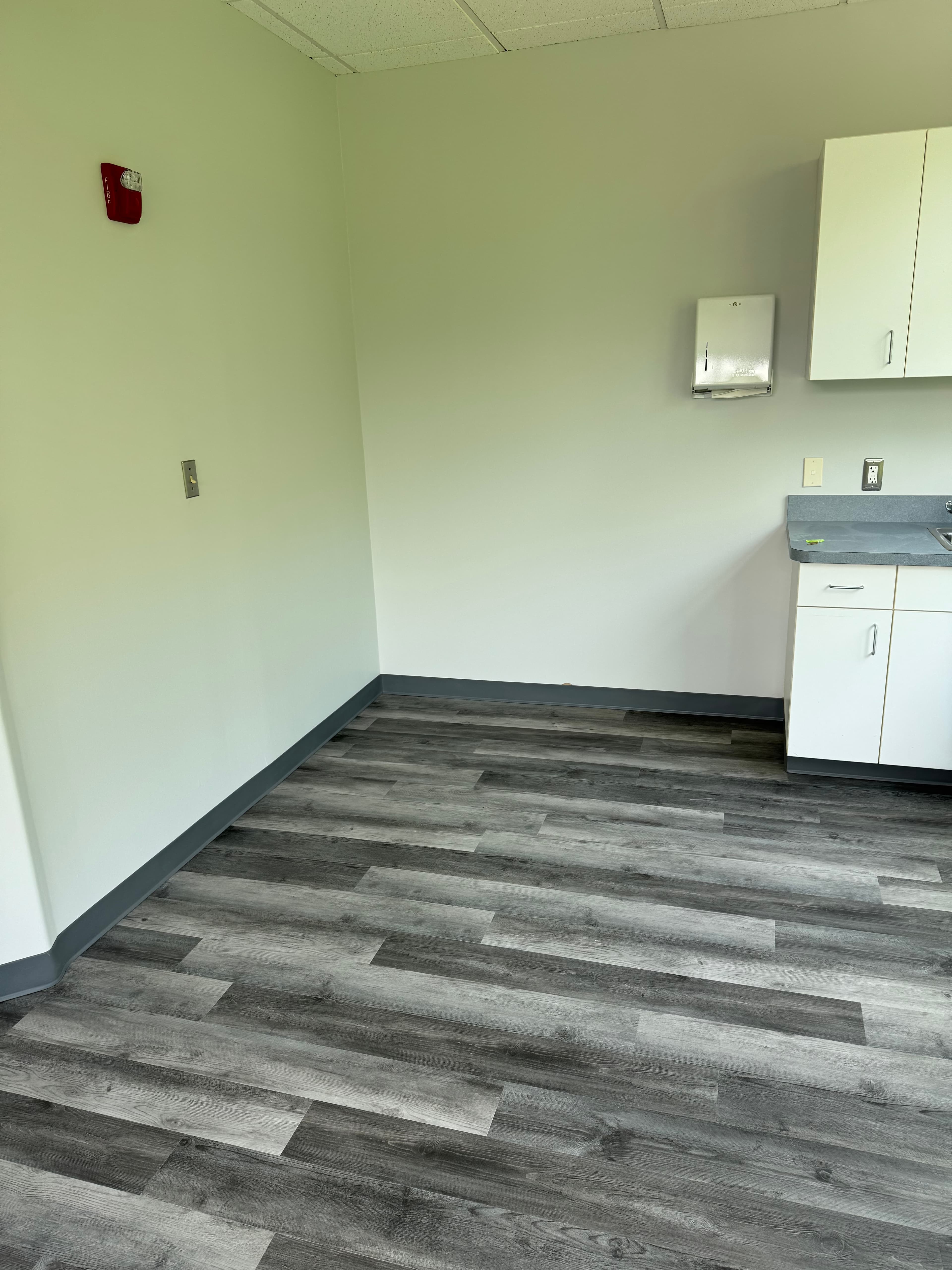 Commercial office break room renovation with gray LVP flooring and white cabinets in Virginia by Atlantic Construction