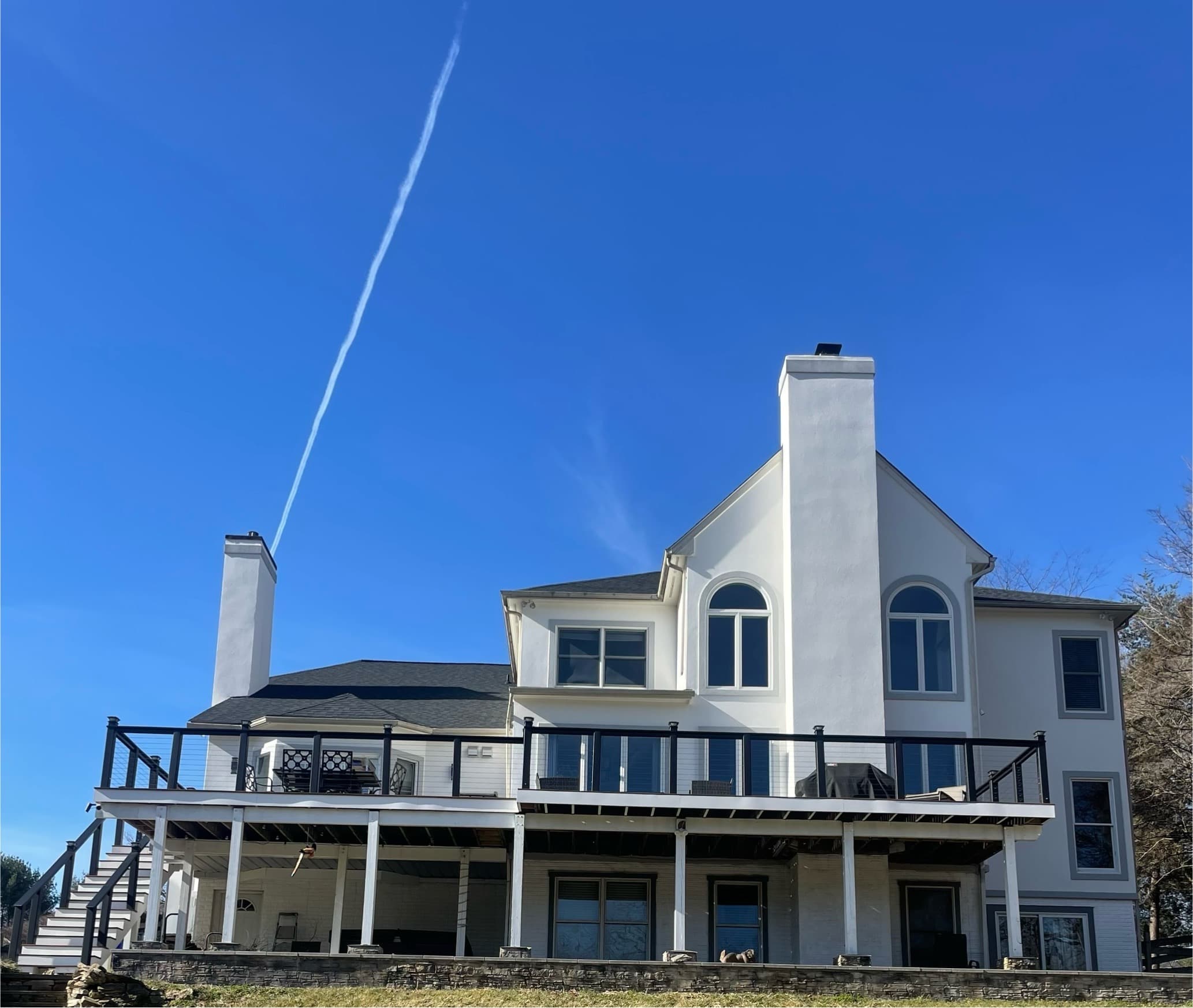 Stunning luxury waterfront home with modern white stucco exterior and black metal deck railings in Maryland by Atlantic Construction