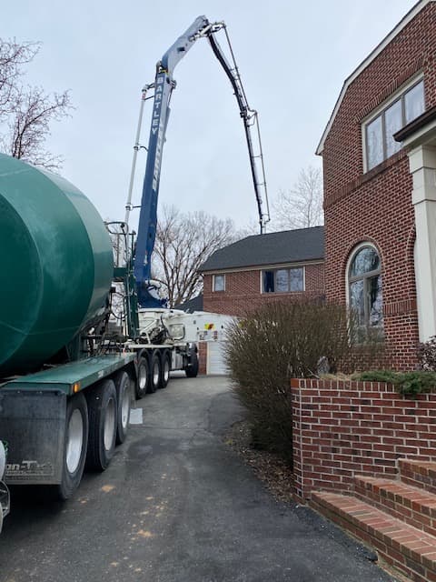 Concrete pump truck delivering for residential driveway project in Maryland by Atlantic Construction
