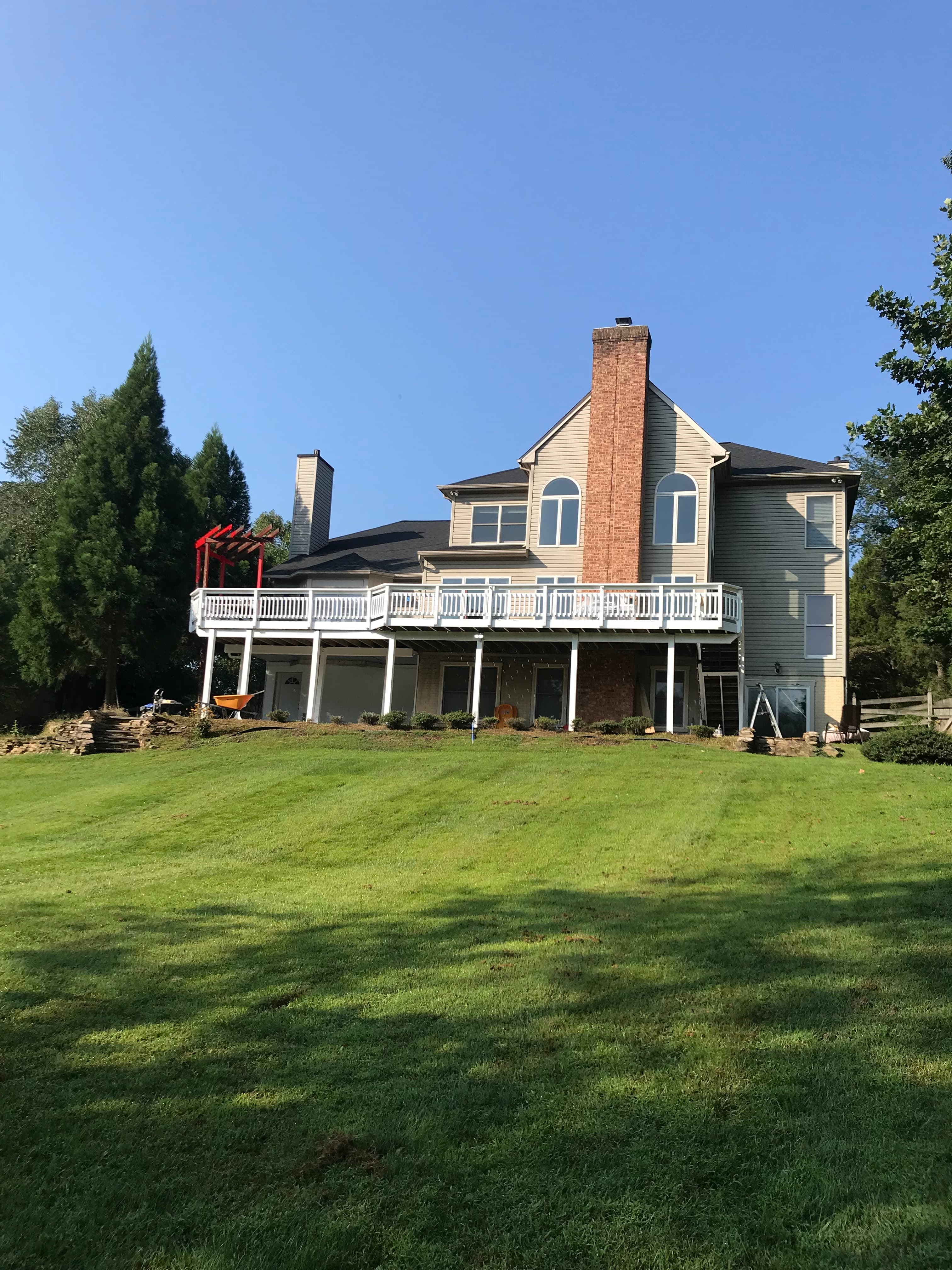 Beautiful residential home with large white railing deck and mature landscaping in Virginia by Atlantic Construction
